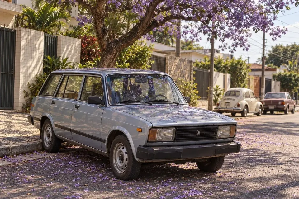 Серебристый универсал Lada 2104 под цветущей жакарандой на улице бразильского города